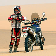 Lonely adventurous female motorcyclist riding motorbike alone in the African desert, Sudan, Africa