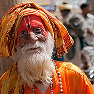 Old Hare Krishna follower dressed in orange dress in front of temple in Govardhan, India