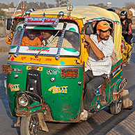 Fully loaded autorickshaw, three-wheeled motorized taxi in busy traffic at Agra, Uttar Pradesh, India